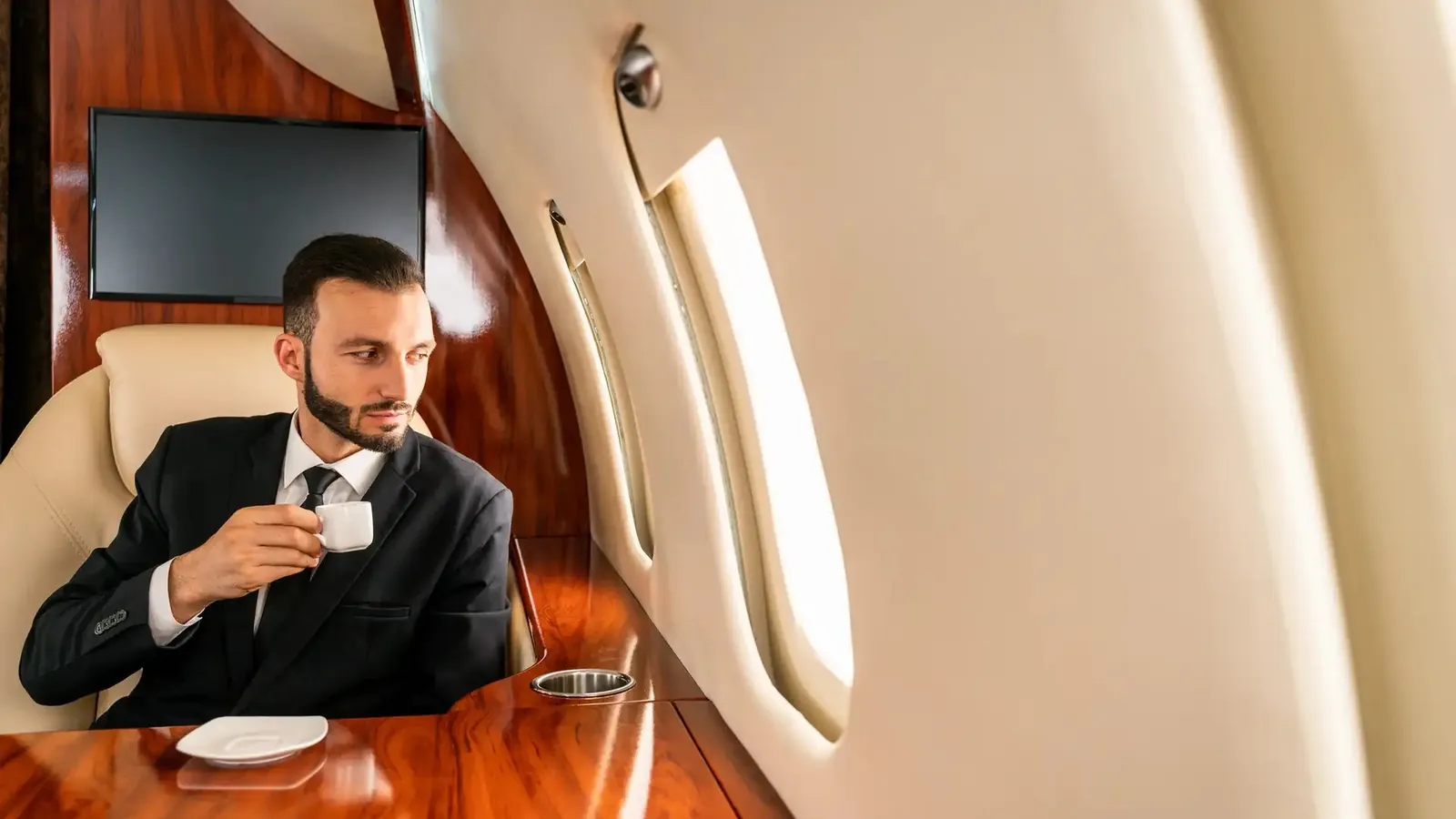 Ein Wagen parkt neben der Treppe eines Business Jets, während eine Reisetasche an Bord getragen wird.
