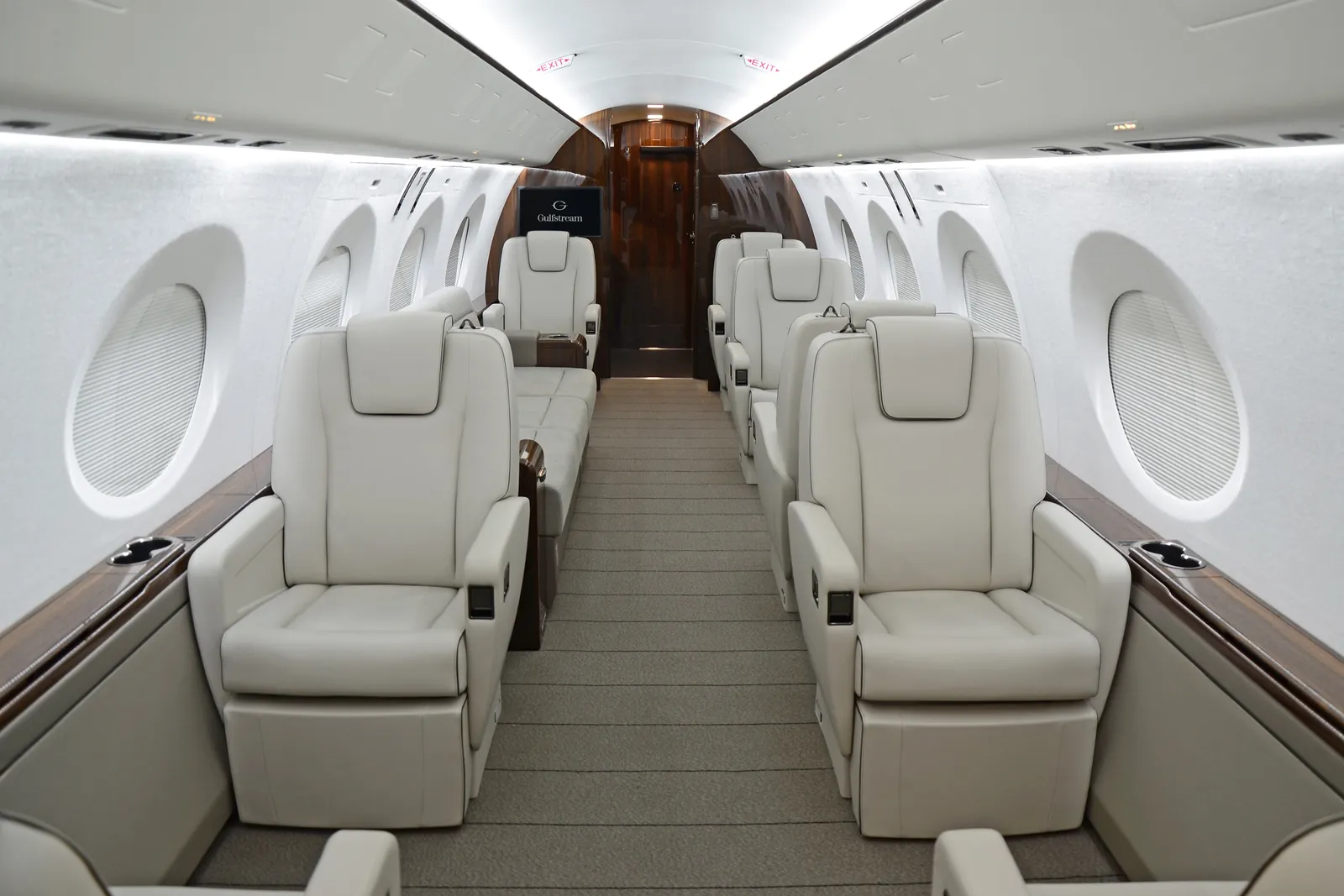 Ausgestattete Kabine der Gulfstream G400 mit cremefarbenen Ledersitzen, Diwan und dunklem Holzfurnier