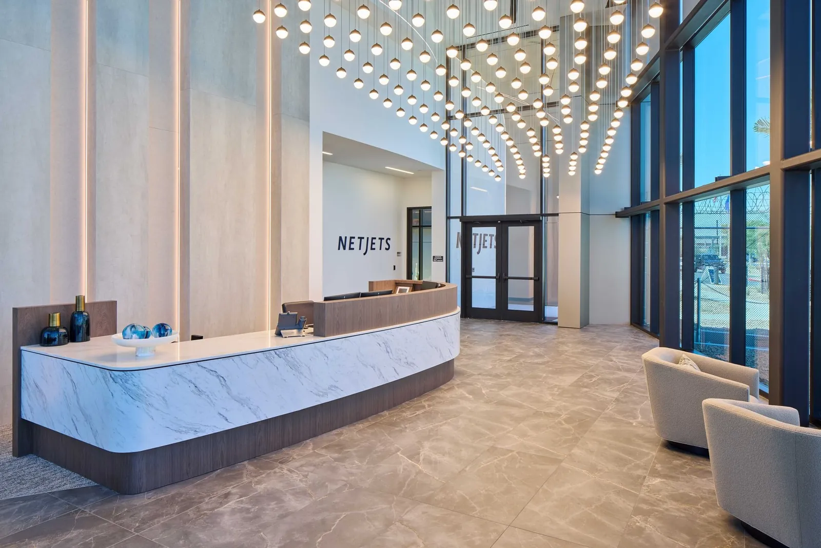Empfangstheke in der Lobby des NetJets-Terminals in Las Vegas unter einer Decke aus Pendelleuchten